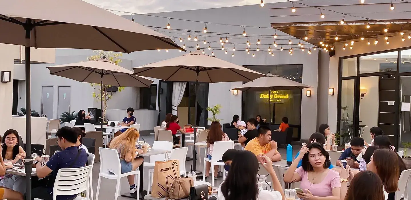 Guests on the Daily Grind Coffee alfresco roof deck under umbrellas and string lights